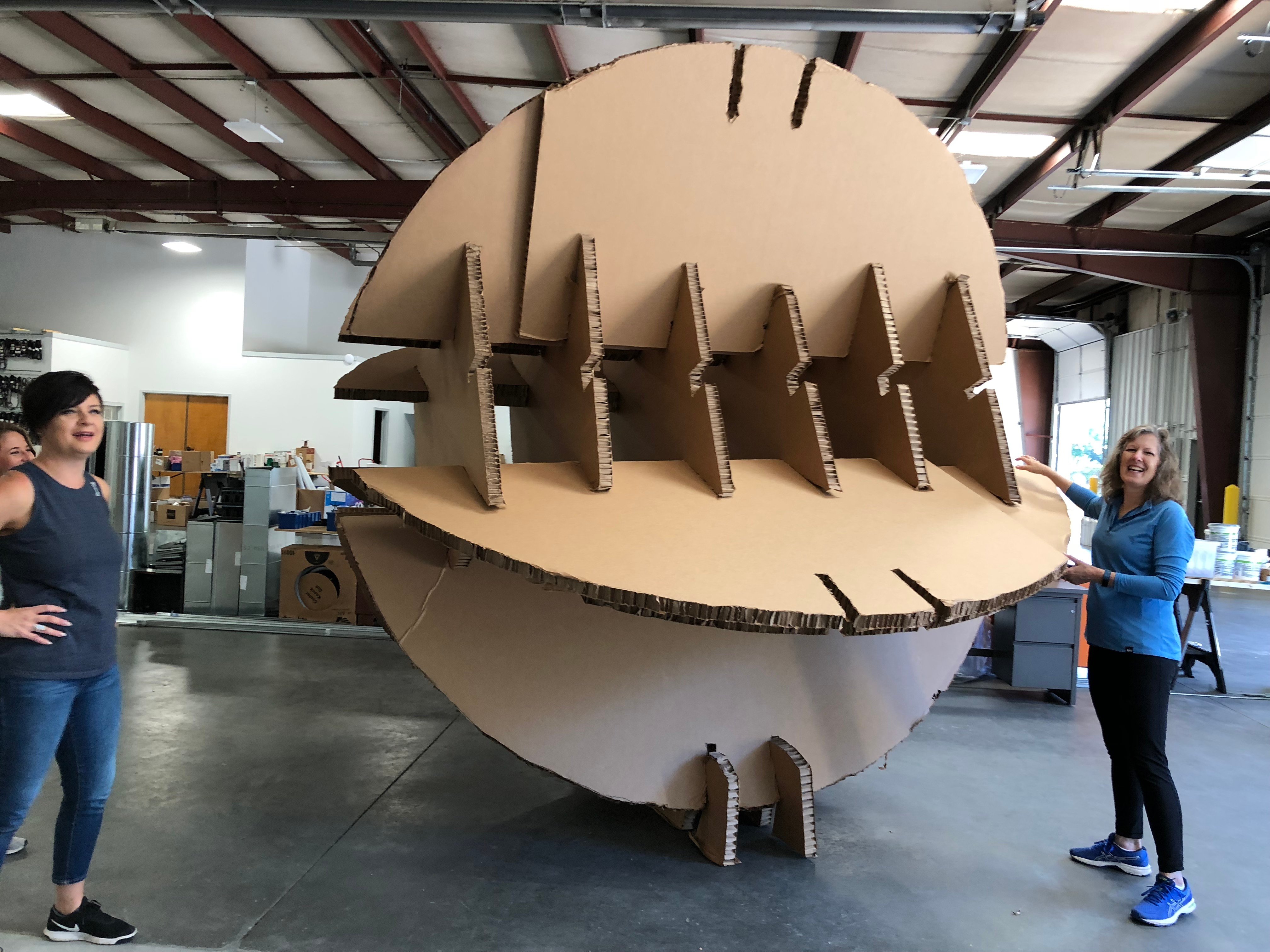 People standing next to the frame for the giant paper ball in construction